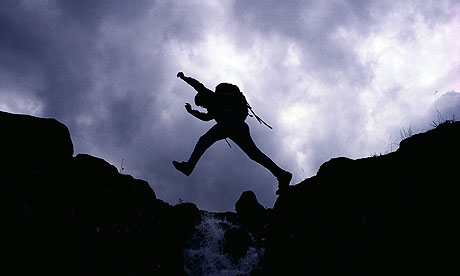 Hiker Jumping over Mountain Stream